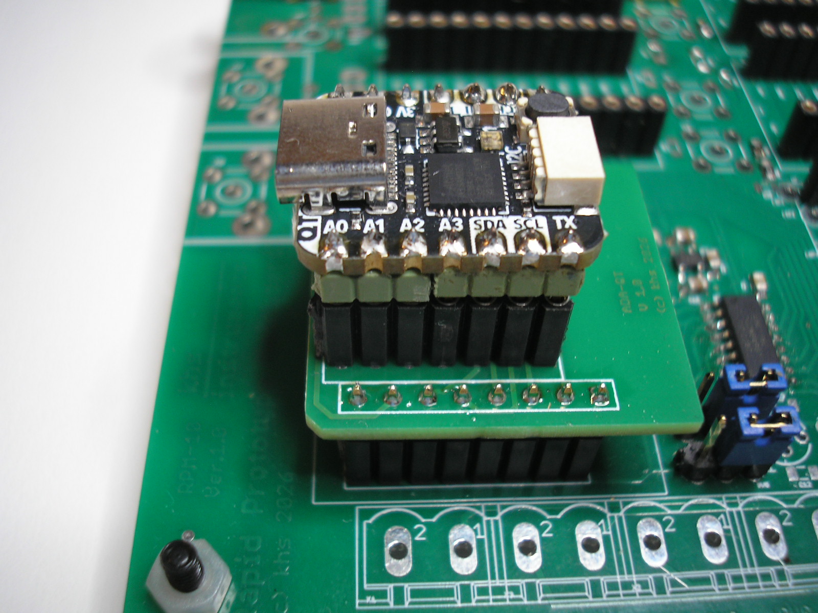 analog::blocks Baseboard with a plug-in adapter carrying an Adafruit QT Py microcontroller board